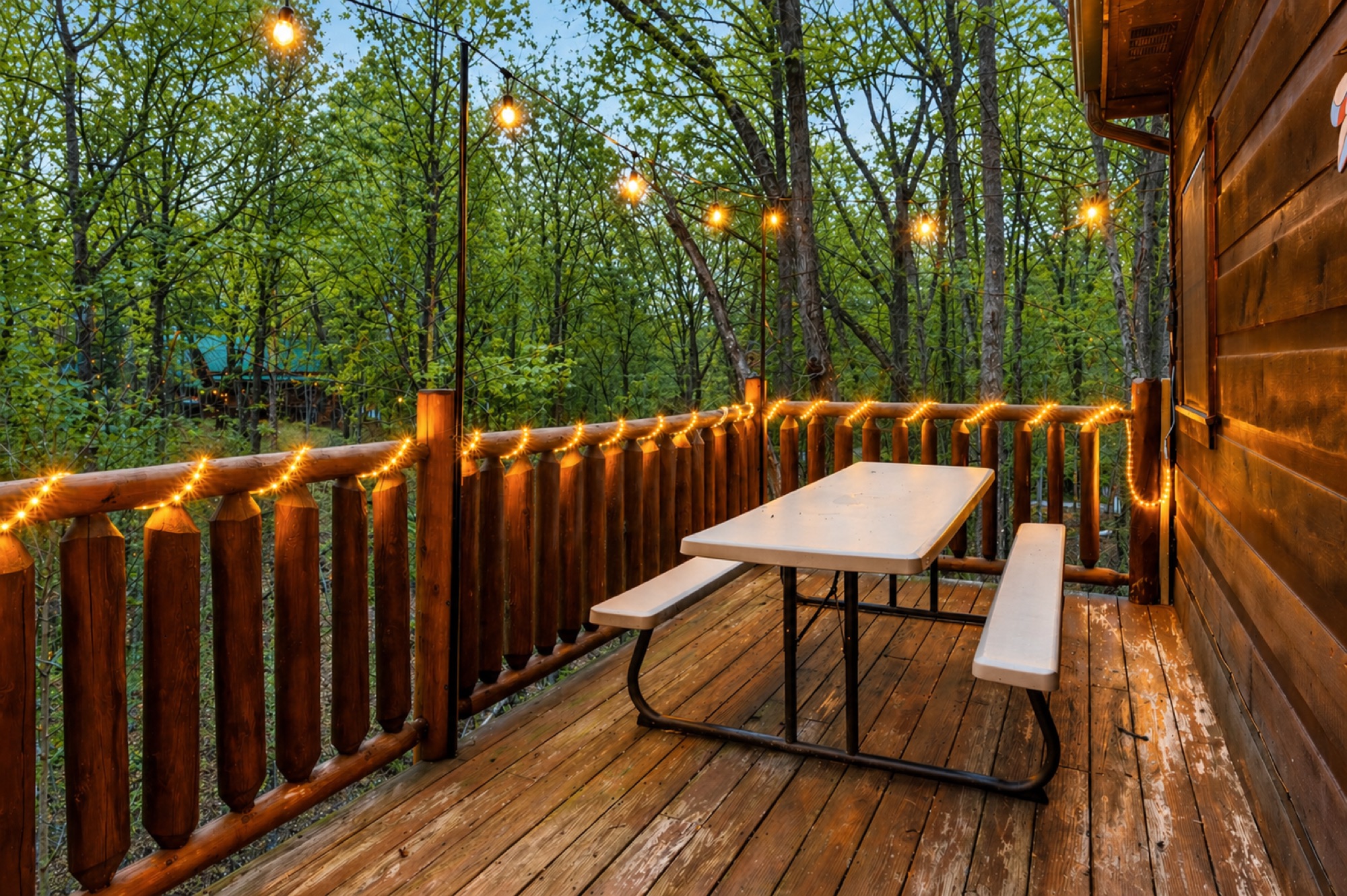 Picnic table on Bearadise's upper deck strung with string lights among the trees